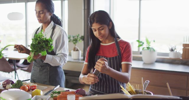 Image of happy diverse female friends cutting vegetables and preparing meal. Friendship, spending quality time together at home.