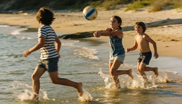 Children playing beach volleyball at golden hour splashing through shallow waves