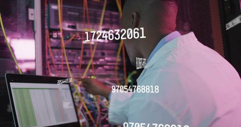 Engineer configuring patch panels at server rack with laptop displaying spreadsheet data
