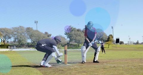 Club cricket batter driving shot with wicketkeeper crouching behind stumps on sunny ground