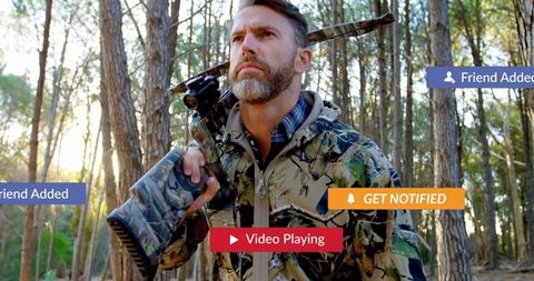 Hunter surveying forest with rifle and tech alerts