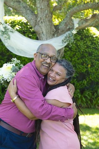 African american senior couple hugging and laughing in sunny garden celebration