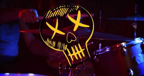 Yellow skull graphic overlay hovering over drum kit in moody low-light concert scene