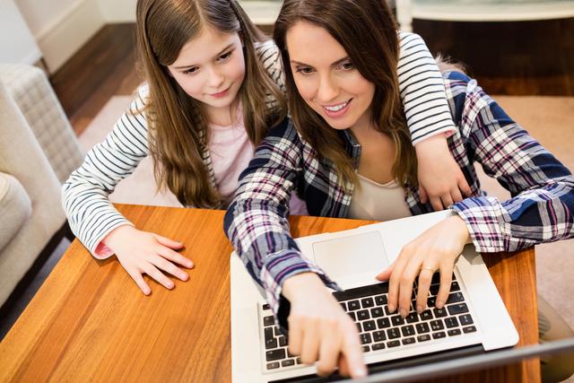 Mother and daughter using laptop in living room at home