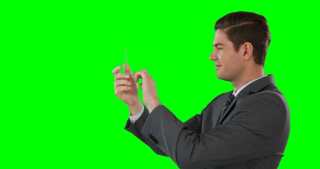 Professional businessman in suit seen using a mobile phone against an isolated green background. Ideal for marketing, business communication, technology-oriented promotions, website banners, or app advertisements.
