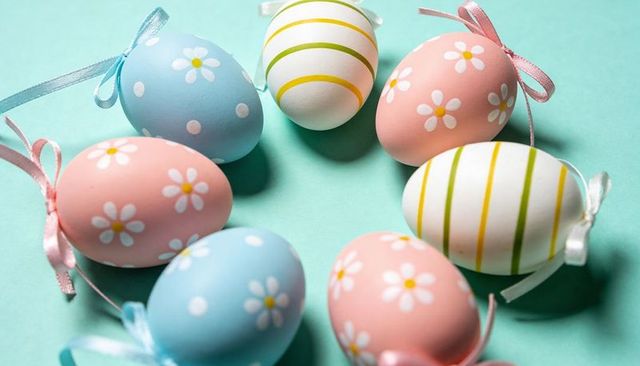 Pastel Easter eggs forming floral wreath on mint background with daisy motifs and ribbons