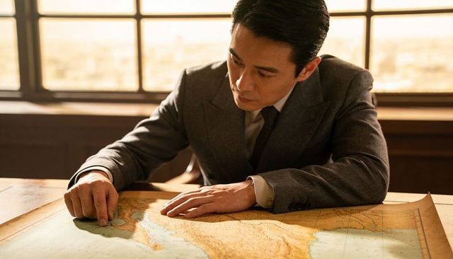 Asian businessman studying antique coastal map in wood-paneled office