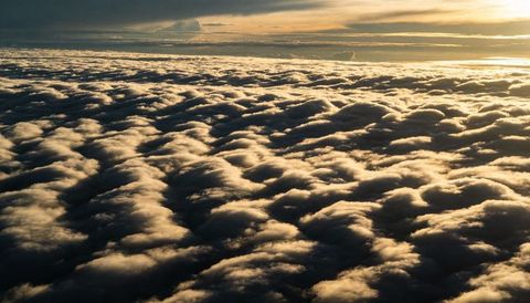 Golden sunrise illuminating rolling stratocumulus cloud deck with textural light and shadow