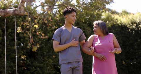 Male Physiotherapist Assisting Senior Woman in Garden Setting