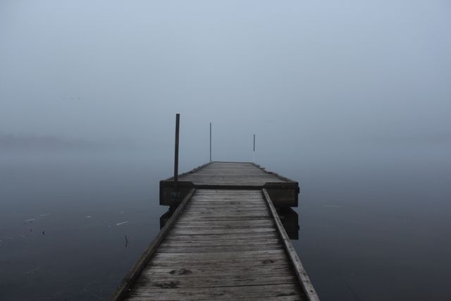 This evocative scene of a wooden dock stretching into a misty lake at dawn can be used for promoting relaxation and tranquility. Perfect for nature-themed backgrounds, promoting mindfulness and meditation products, or in publications about serene travel destinations. The foggy atmosphere adds a mysterious and calm mood to the visual storytelling.