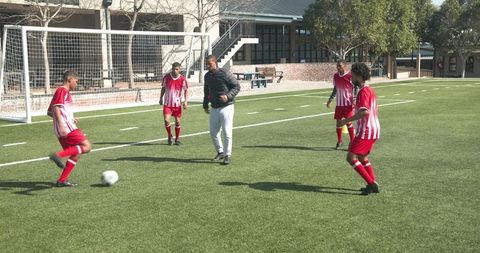 Coach training youth soccer players on school field