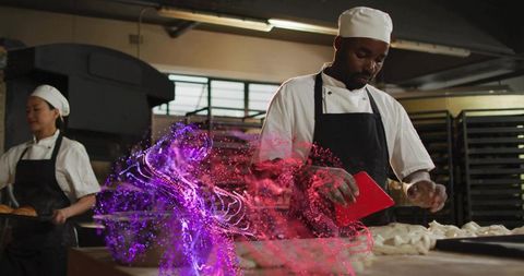 Kneading dough with red bench scraper in industrial bakery, bakers collaborating