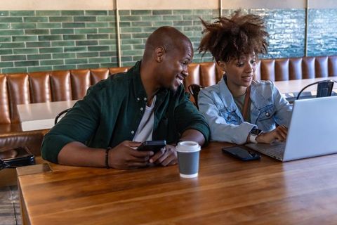 African american friends collaborating on laptop in cafe, coffee cup, casual coworking energy