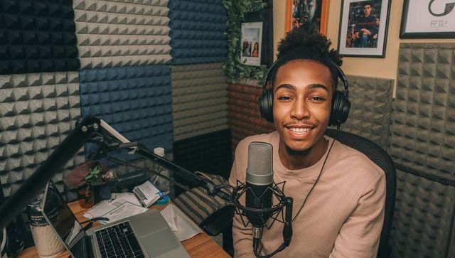 Black podcaster recording in home studio with microphone, headphones and acoustic foam