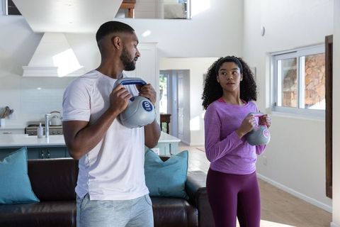 Diverse Couple Exercising with Kettlebells in Modern Home Living Area