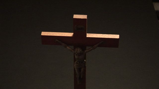 This image features a wooden crucifix prominently displayed against a dark background. Ideal for use in religious studies, church presentations, articles about Christian symbolism, or discussions regarding faith and spirituality.