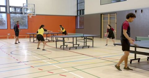 Diverse group engaged in table tennis match in gym