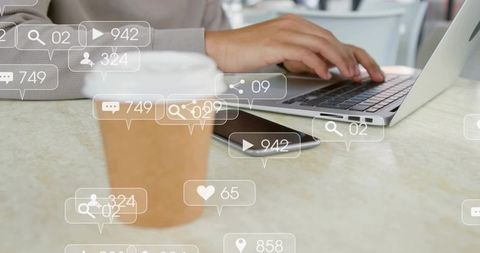 Man typing on laptop in cafe with smartphone and coffee cup with social media overlay