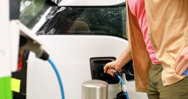 A person is refueling their car at a gas station, with copy space. This everyday scene captures a routine aspect of vehicle maintenance and the reliance on fuel for transportation.
