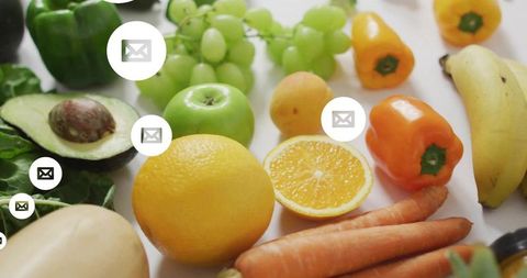 Bright assorted fruits, vegetables displaying halved avocado and orange with email icons