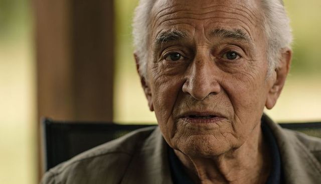 Contemplative senior man on porch close-up portrait showing weathered wrinkles and thoughtful gaze