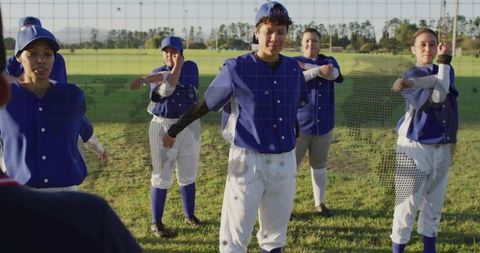 Female Baseball Players Stretching in Blue Uniforms on Field