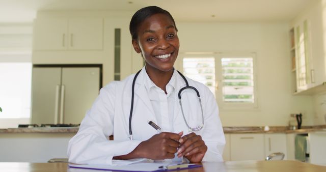 Smiling Female Doctor Taking Notes in Kitchen Setting - Download Free Stock Images Pikwizard.com