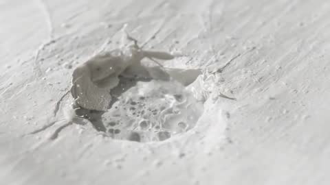 Macro video showing bubbling plaster crater with lifting flakes and glossy foam
