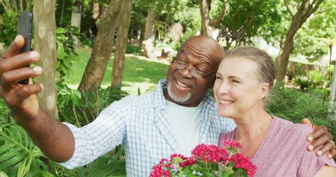Happy Senior Couple Taking Selfie in Lush Garden Setting