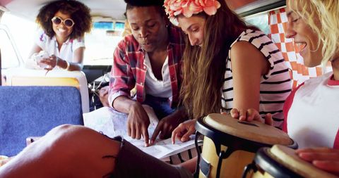 Happy young adults planning road trip adventure in colorful van