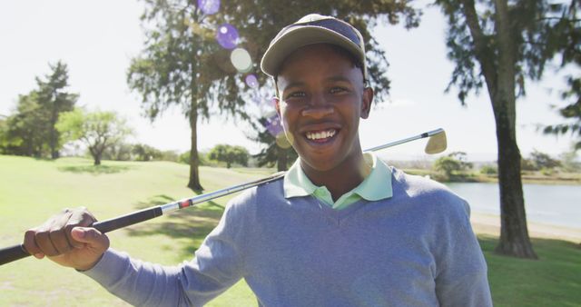 Image of happy african american man holding golf club on golf filed. sporty, active lifestyle and playing golf concept.