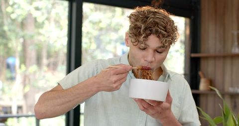 Modern kitchen with person eating noodles by large window