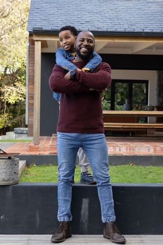African american father and son sharing hug on modern porch, smiling and bonding