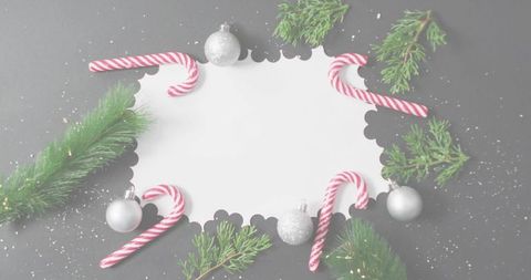 Displaying scalloped greeting card surrounded by candy canes, silver baubles and pine sprigs