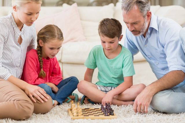 Family enjoying a game of chess in their living room. Parents and children are sitting on the floor, focusing on the chessboard. Ideal for concepts related to family bonding, indoor activities, strategic thinking, and quality time at home.