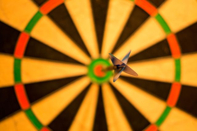Close-up shot showcasing a dart hitting the bullseye in the center of a dartboard. Ideal for themes of success, precision, accuracy, aiming, competitive sports, and goal achievement. Useful for illustrating concepts in presentations, posters, and sports advertisements.