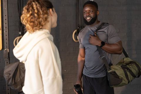 Post-workout chat between gym buddies carrying duffel bag and shaker bottle
