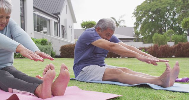 Senior couple engaging in yoga stretching exercises on mats in grassy lawn outside their home. Ideal for concepts related to healthy living, active seniors, promoting fitness, and wellness routines. Can be used in health and wellness articles, retirement community brochures, or fitness magazines.
