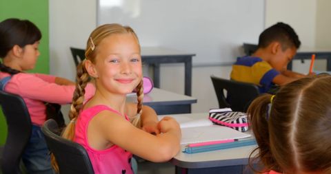 Joyful Schoolgirl with Blonde Braids Learning in Classroom