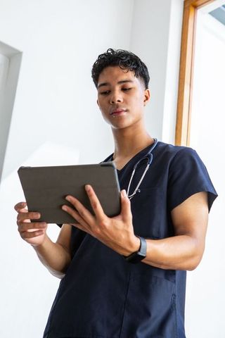 Focused young doctor reviewing medical information on tablet