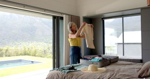 Senior woman packing for beach vacation with scenic view