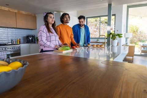 Multicultural friends preparing burgers on modern kitchen island with fresh ingredients
