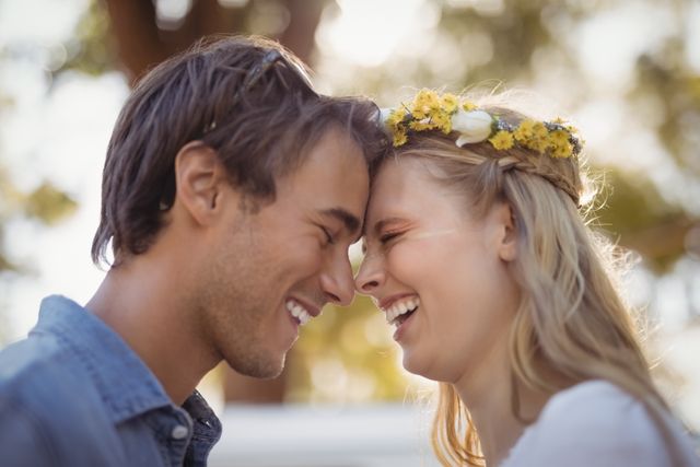 Young couple standing face to face, laughing and enjoying each other's company outdoors. Perfect for use in advertisements, relationship blogs, social media posts, and lifestyle magazines to convey themes of love, happiness, and togetherness.