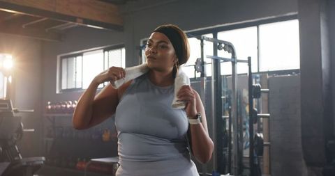 Confident woman cooling down after strength workout in sunlit industrial gym