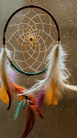 Swaying dreamcatcher with colorful feathers in rainy window vertical bohemian calm video