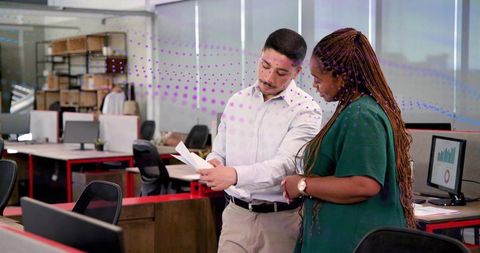 Colleagues reviewing documents in modern open-plan office discussing business strategy