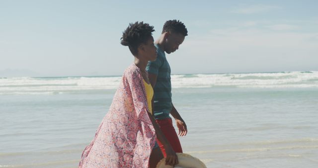 An African couple walking on a beach, holding hats, and enjoying a peaceful summer day. Ocean waves and serene environment in the background. Ideal for concepts of vacation, friendship, romance, leisure activities, and promoting beach destinations.