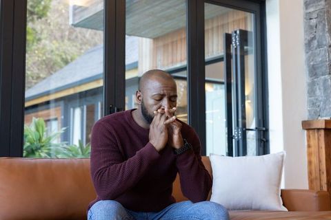 Middle-aged african american man reflecting on sofa in modern living room