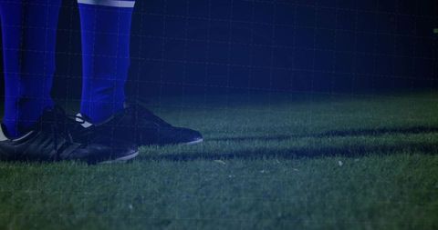 Athlete on night field in blue socks and black cleats