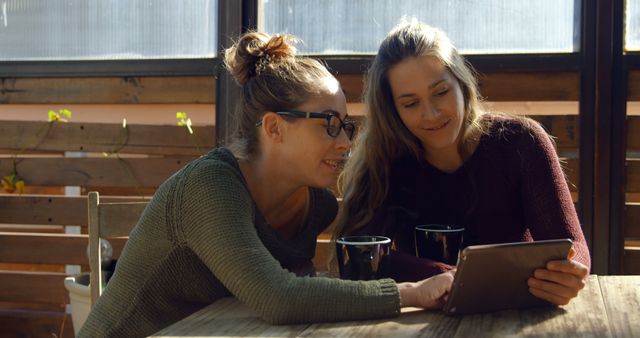 Two young Caucasian women are sharing a moment looking at a tablet together, with copy space - Download Free Stock Photos Pikwizard.com